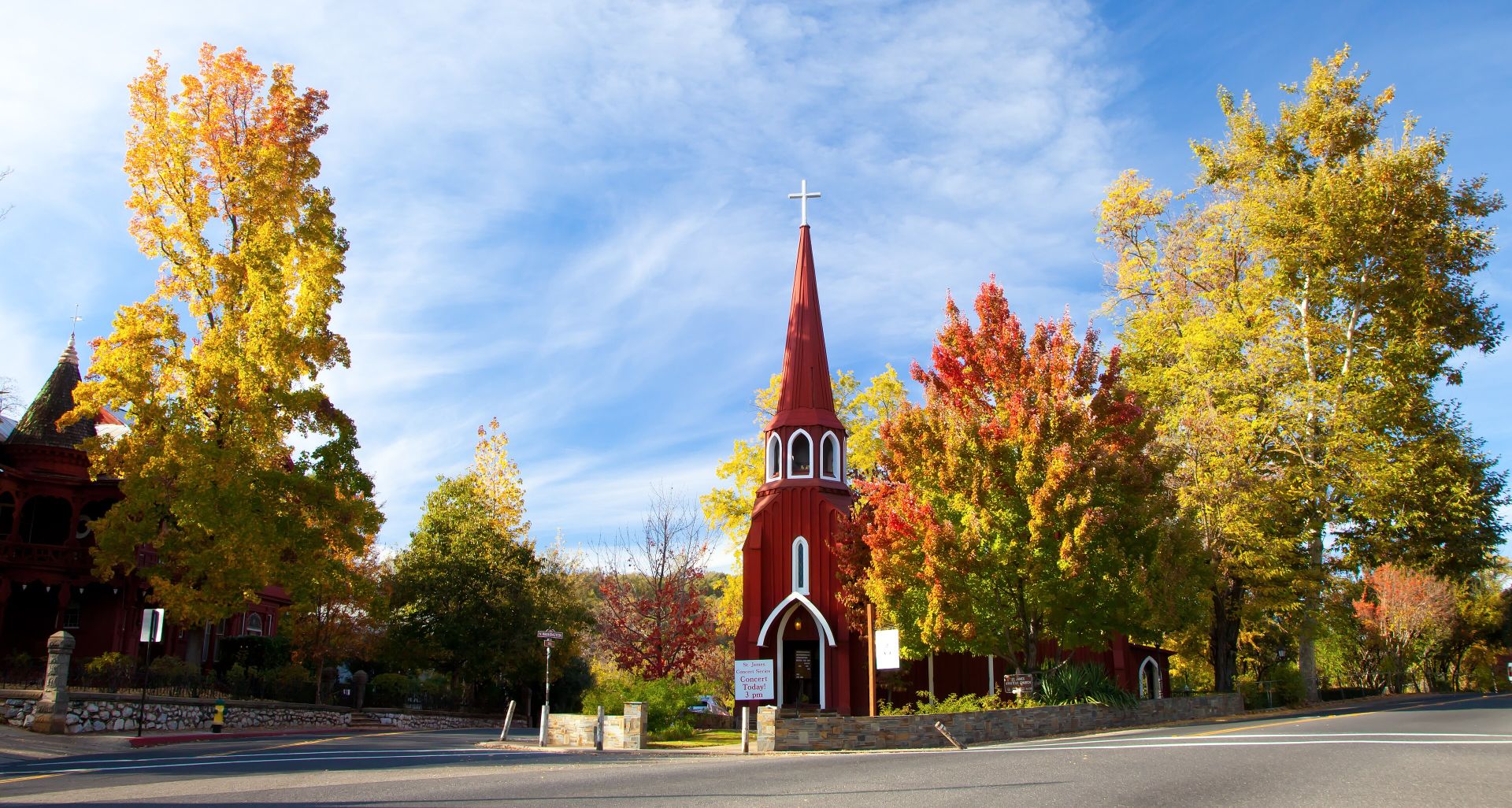 The red St. James Episcopal Church in Sonora framed by autumn trees